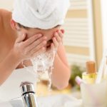 Woman splashing face with water in bathroom